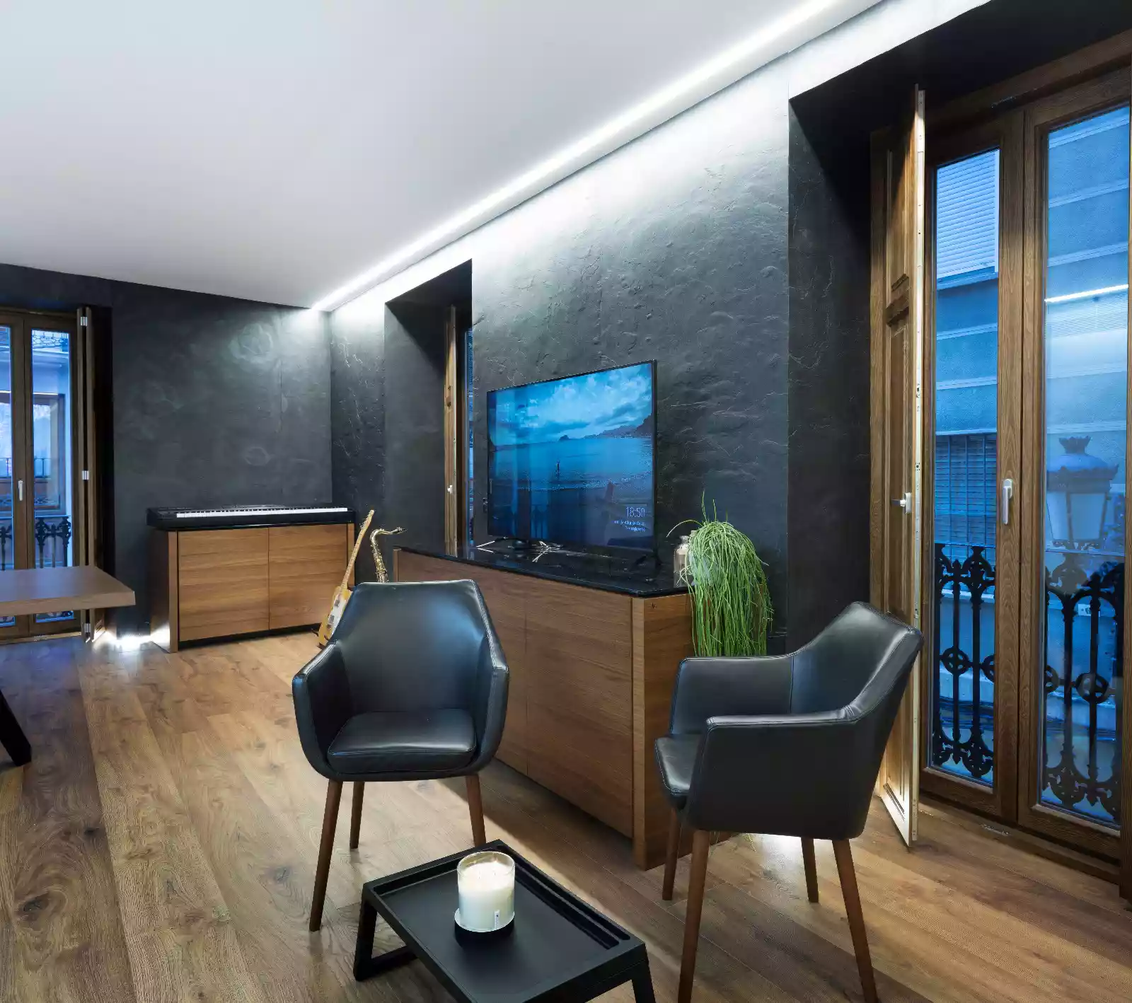Salón diáfano y transformable de la Casa Calza en Valencia, con carpintería blanca lacada, suelos de madera y detalles en pizarra negra. | E6A